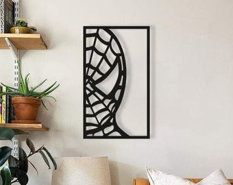 May include: Black metal wall art featuring a silhouette of Spider-Man's face with a web design. The art is framed in a black rectangle and is hanging on a white wall.