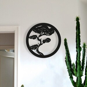 May include: A bright red metal cabinet with two doors and a keyhole, topped with a silver decorative plate and potted plants. A black tree silhouette hangs on the white wall above the cabinet.