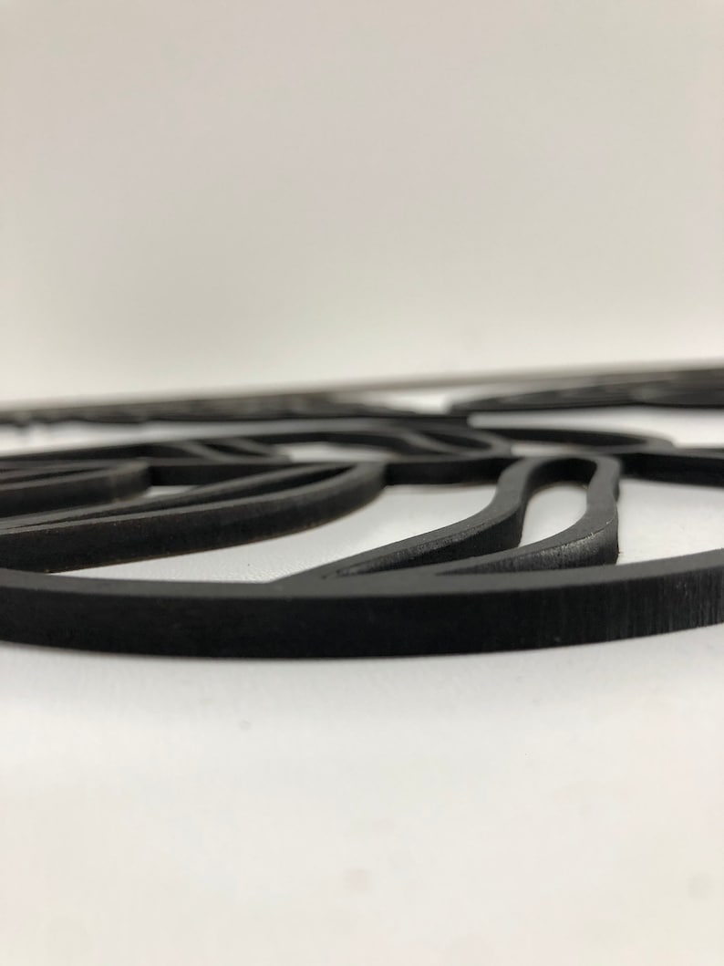 以下が含まれることがあります： 黒色のレーザーカット装飾品。葉のようなデザインで、マットな仕上がり。白い背景に配置され、曲線と丸みを帯びたエッジが特徴です。