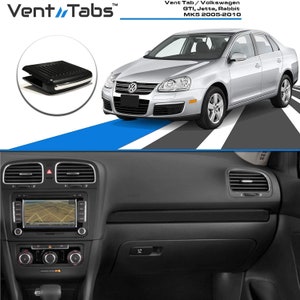 May include: A black Vent Tab for Volkswagen GTI, Jetta, and Rabbit MK5 models from 2005-2010. The image shows the product, a car, and the car's interior. The product is a black plastic vent tab with a silver trim.
