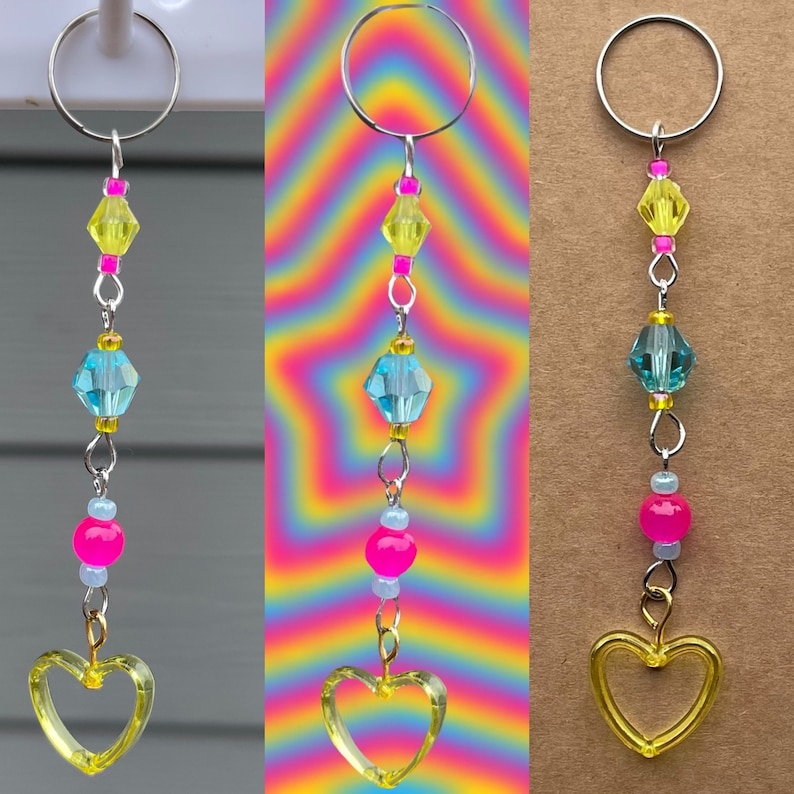 May include: A silver key chain with a yellow heart charm, blue and pink beads, and yellow and pink crystal beads.