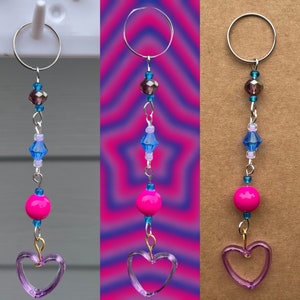 May include: A silver key chain with a purple heart charm, pink and blue beads, and a silver ring at the top.