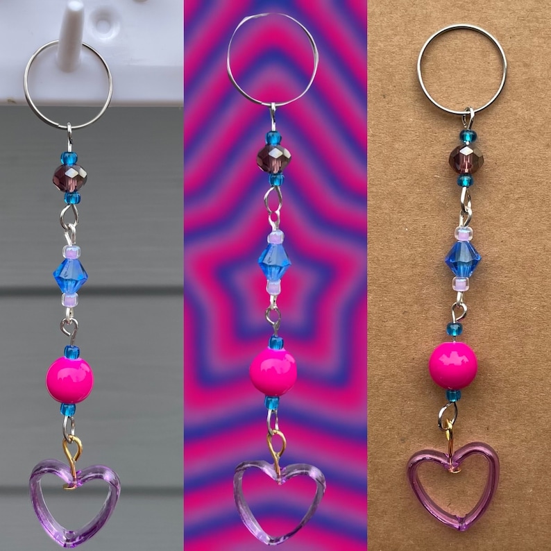 May include: A silver key chain with a purple heart charm, pink and blue beads, and a silver ring at the top.