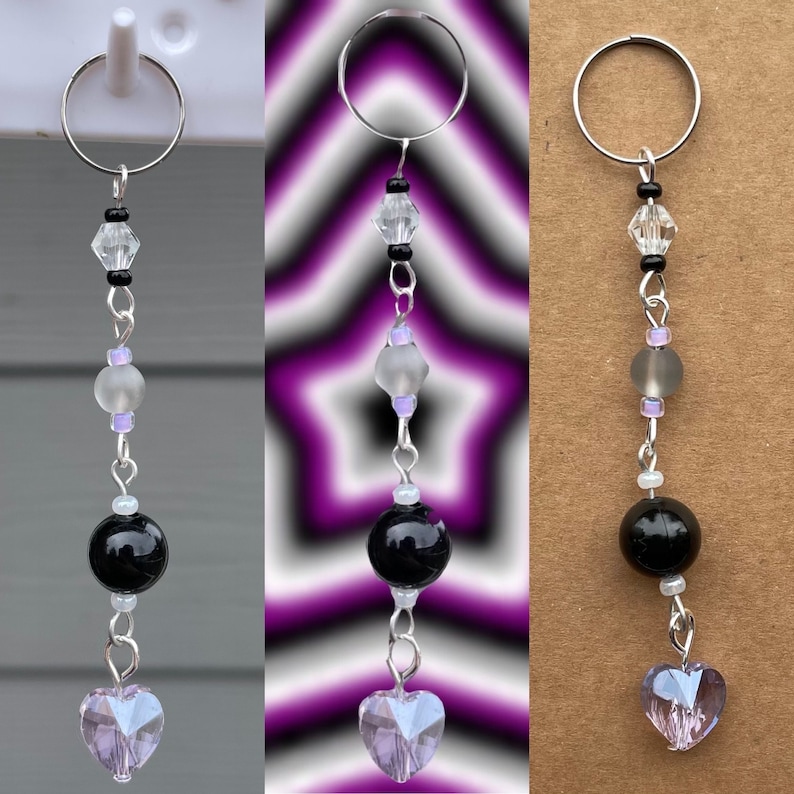 May include: A silver key chain with a black and white crystal heart charm. The charm is attached to a silver chain with black and white beads, a frosted white bead, and a black bead.
