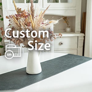 Pode incluir: Um arranjo floral seco em um jarro branco sobre um corredor de mesa cinza. O arranjo inclui ervas secas, grama da pampa e outras flores secas. O texto "Custom Size" é sobreposto à imagem.