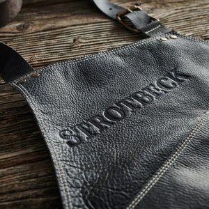 May include: Black leather apron with white stitching and the word "STROWBACK" embossed in the center.