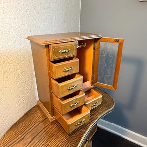 Se trata de un joyero/mini tocador de madera vintage de mediados a finales del siglo XX, marcado “Linden – Taiwán”.