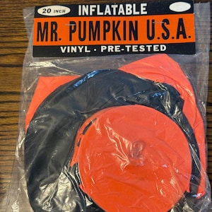 Könnte beinhalten: Aufblasbare Mr. Pumpkin U.S.A. Dekoration, ca. 51 cm groß, verpackt in einer transparenten Plastiktüte. Der Kürbis ist orange und schwarz, aus Vinyl und vorgestestet.