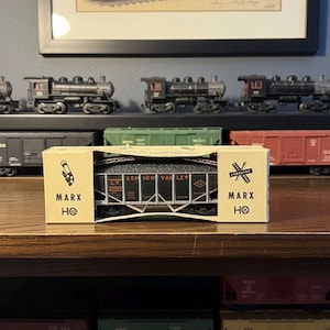 May include: A Marx HO scale model train car in its original box. The box is tan with the Marx logo and a graphic of a train crossing. The train car is black with the words "Lehigh Valley" printed on the side.