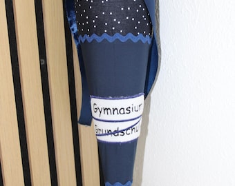 Könnte beinhalten: Eine marineblaue Schultüte mit weißen Punkten und passendem Band. Auf der Tüte steht "Gymnasium Grundschu". Die Tüte ist etwa 50 cm hoch.