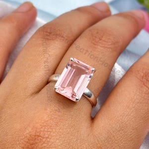 Puede incluir: Un anillo de plata con una gran piedra preciosa rosa pálida de talla esmeralda.