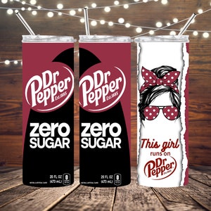 以下が含まれることがあります： Dr Pepperをテーマにしたステンレス製のタンブラー3つ。最初の2つのタンブラーは、赤と黒で、Dr Pepperのロゴと「ゼロシュガー」の文字が書かれています。3つ目のタンブラーは白で、赤いヘッドバンドとサングラスをかけた女性の漫画のイラストと「This girl runs on Dr Pepper」の文字が書かれています。