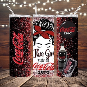 Puede incluir: Un vaso de acero inoxidable con un diseño de purpurina roja y negra. El vaso presenta un gráfico de una mujer con un moño y el texto "This Girl Runs on Coca-Cola Zero".