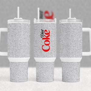 May include: Three silver glitter insulated tumblers with white lids and handles. The center tumbler has the words "Diet Coke" printed in red on the side.