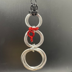 May include: A silver wire snowman ornament with a black wire hat and a red wire scarf.