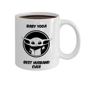 Puede incluir: Taza de caf&eacute; de cer&aacute;mica blanca con una imagen en blanco y negro de Baby Yoda. La taza tiene el texto "Baby Yoda" y "Best Husband Ever" impreso en ella.