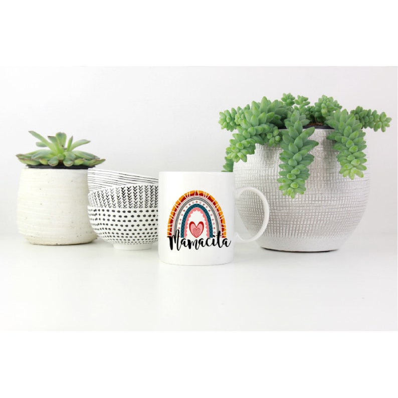 Puede incluir: Taza de cer&aacute;mica blanca con un dise&ntilde;o de arco&iacute;ris colorido y la palabra "Mamacita" impresa en la parte delantera.