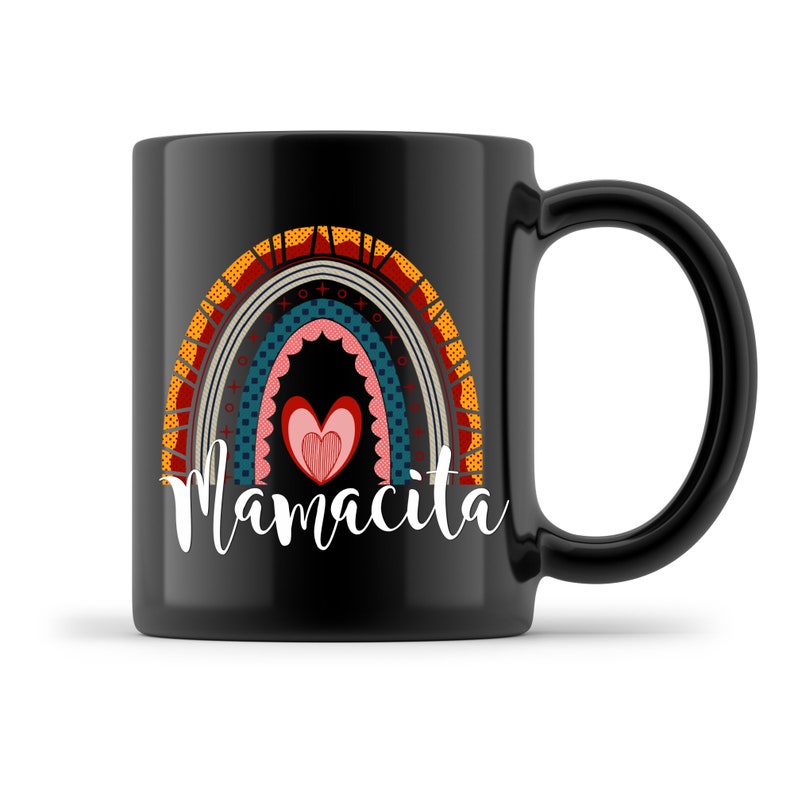 Puede incluir: Taza de caf&eacute; de cer&aacute;mica negra con un dise&ntilde;o de arco&iacute;ris y la palabra "Mamacita" en letras blancas. El arco&iacute;ris est&aacute; formado por diferentes rayas de colores con un coraz&oacute;n en el centro.