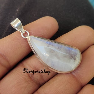 Puede incluir: Un colgante de piedra lunar en forma de l&aacute;grima engastado en plata de ley. La piedra es de color blanco lechoso con un brillo iridiscente azul.