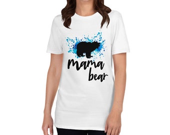 Puede incluir: Camiseta blanca con un diseño de salpicaduras de acuarela azul y una silueta negra de un oso. El texto "mama bear" está impreso debajo del oso.