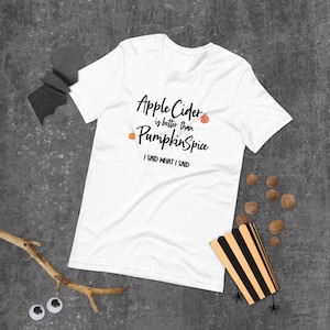 May include: White t-shirt with the text "Apple Cider is better than Pumpkin Spice I said what I said" and a small orange pumpkin graphic.