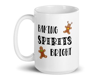 May include: White ceramic mug with a black and brown gingerbread man design. The mug reads "Baking Spirits Bright".