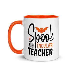 Puede incluir: Taza de caf&eacute; blanca con borde y asa naranja. La taza tiene un gr&aacute;fico negro que dice "Spooktacular Teacher" con un dise&ntilde;o de murci&eacute;lago y telara&ntilde;a.
