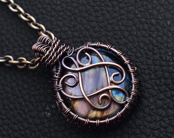 May include: A copper wire wrapped pendant featuring a round iridescent labradorite gemstone. The wire is twisted into a Celtic knot design.