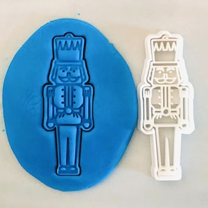 Könnte beinhalten: Ein blauer Plastik-Ausstecher in Form eines Nussknackers. Der Ausstecher ist mit einem Hut, einem Schnurrbart und einem Schwert verziert.