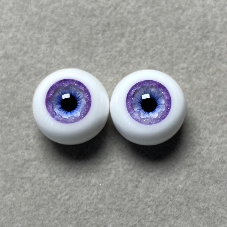 May include: Two purple and white doll eyes with a blue iris and a glitter finish.