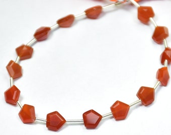 May include: A strand of carnelian gemstone beads, each bead is faceted and has a reddish-orange color. The beads are strung on a silver wire.