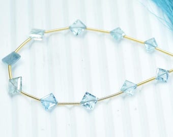 May include: A necklace featuring light blue, square-cut gemstones strung on a gold-colored wire. The gemstones are evenly spaced. A light blue tassel is attached to the end of the necklace.