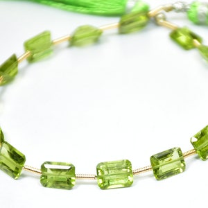 May include: A strand of green peridot beads strung on a gold wire. The beads are rectangular and faceted.