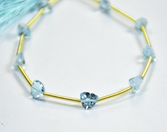 May include: A strand of light blue gemstone beads strung on a gold wire. The beads are triangular in shape and have a faceted finish.