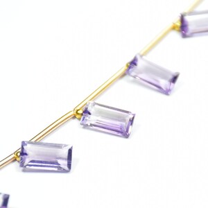 May include: A strand of gold chain with purple amethyst gemstone beads. The beads are rectangular and faceted.