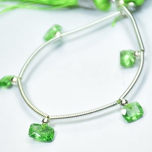 May include: A silver chain bracelet with five green gemstone charms. The gemstones are square-shaped and have a faceted cut.