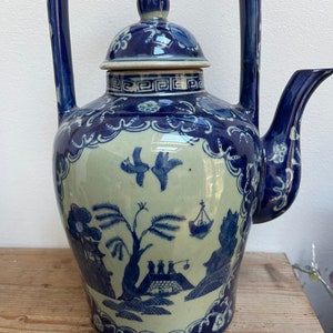 以下が含まれることがあります： 蓋と取っ手のある青と白の磁器製のティーポット。ティーポットは、風景とボートを描いた伝統的な中国のデザインです。