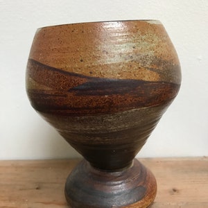 Könnte beinhalten: Eine braune und weiße Keramikvase mit einem ausgestellten oberen Teil und einem abgerundeten Boden. Die Vase hat eine marmorierte Glasur mit braunen, weißen und grauen Streifen.