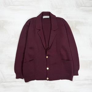 May include: A deep burgundy knit cardigan featuring a notched lapel collar, long sleeves, and three gold-toned buttons down the front. The garment includes two front patch pockets and a white label at the inner neckline with the text Burberrys.