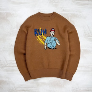 Puede incluir: Suéter marrón de cuello redondo con diseño de punto. El diseño incluye la palabra "RUN" en azul y un personaje de dibujos animados con camisa azul y gorra roja. El suéter tiene mangas largas y dobladillo acanalado.