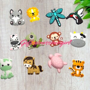 May include: A collection of colorful animal-themed charms, including a gray wolf, yellow lion, blue dragonfly, hummingbird, zebra, green turtle, monkey, cow, green cow, horse, pink turtle, and orange tiger.
