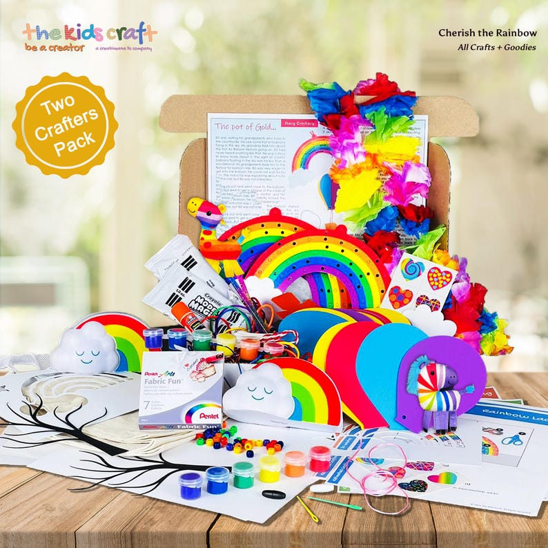 K&ouml;nnte beinhalten: Ein Bastelset mit Regenbogen-Thema, das eine Vielzahl farbenfroher Materialien enth&auml;lt. Das Set beinhaltet regenbogenf&ouml;rmige Aussparungen, Farbe, Stoff und andere Bastelmaterialien. Die Box ist ge&ouml;ffnet und zeigt den Inhalt auf einer Holzoberfl&auml;che. Der Text lautet "Cherish the Rainbow."