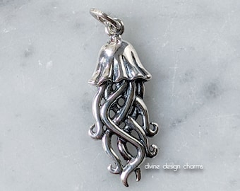 May include: A silver charm in the shape of a jellyfish with intricate, detailed tentacles. The charm is designed with a Celtic knot pattern.