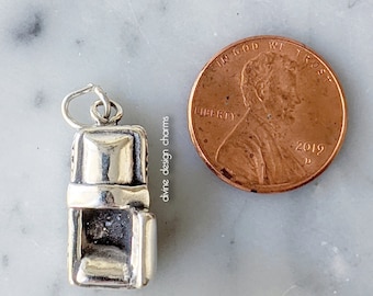 May include: Silver charm in the shape of a reclining chair. The charm is about the size of a US penny.