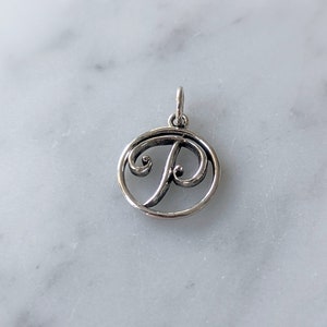 May include: Silver charm with a cursive letter P in a circle.