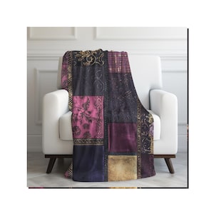 May include: A patchwork throw blanket draped over a white armchair. The blanket features a mix of patterned squares in shades of purple, pink, gold, and black. The design includes floral and geometric patterns.