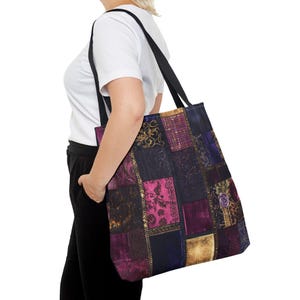 Puede incluir: Un bolso tote de patchwork con una correa negra. La bolsa presenta una variedad de cuadrados de tela en tonos morado, dorado y azul marino. Algunos cuadrados tienen patrones florales y de damasco.