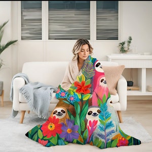 May include: A colorful throw blanket featuring a tropical jungle scene with sloths, flowers, and lush greenery. The blanket is made of soft, plush fabric and is perfect for adding a touch of whimsy to any room.