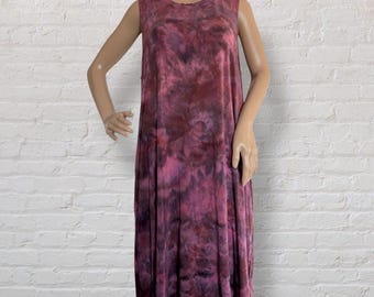 May include: A sleeveless, knee-length dress with a tie-dye pattern in shades of pink and burgundy. The dress has a round neckline and a loose, flowing fit. The fabric appears soft and comfortable, suitable for casual wear.