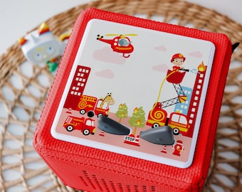 May include: Red and white toy fire truck with a black and gray handle. The toy has a red and white helicopter, a giraffe, and a fireman on a ladder. The toy has the word "STOP" and "FEUERWEHR" printed on it.
